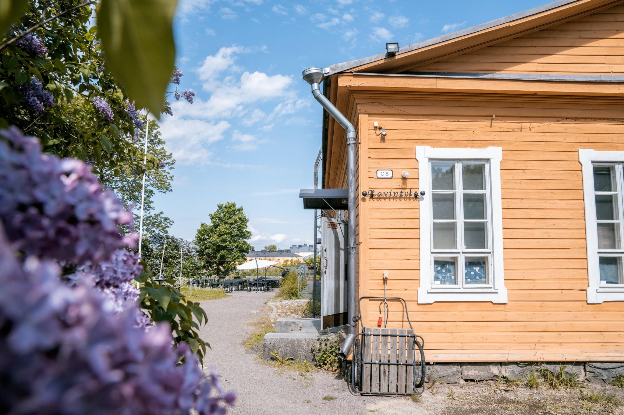 Bastion Bistro kuvattuna olkoapäin. Rakennus, jonka vieressä näkyy kasveja. Taustalla näkyy sininen taivas.
