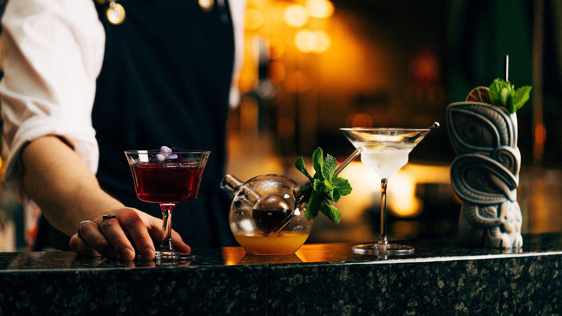 American Bar. Kuvassa näkyy henkilö, jonka edessä on useita drinkkejä.