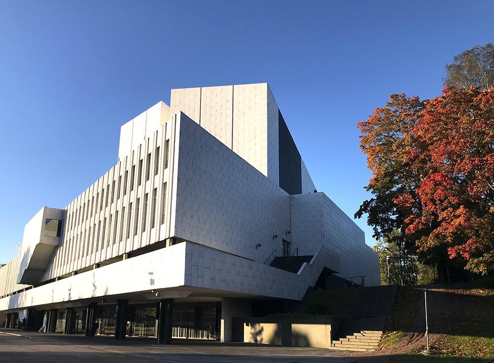Finlandia-huset, fotograferat utifrån. Bredvid byggnaden finns ett träd, och i bakgrunden syns blå himmel.