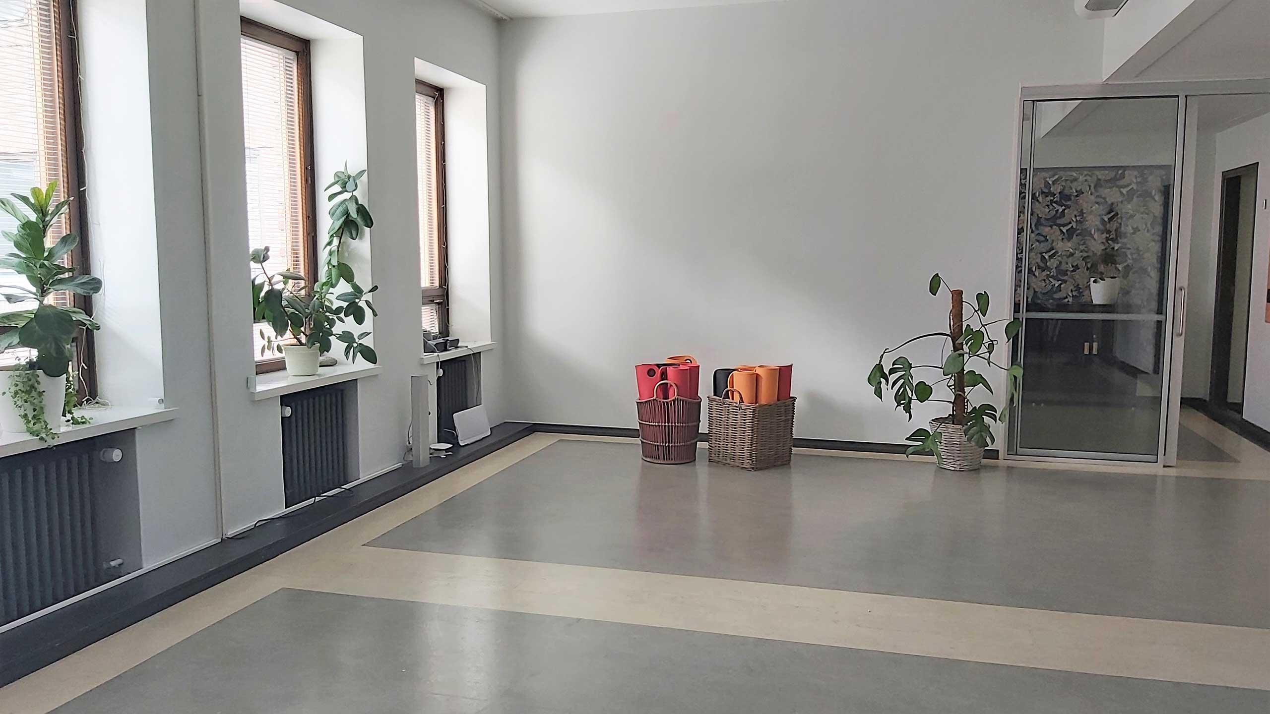 An open hall with gym mats in a basket on the floor.