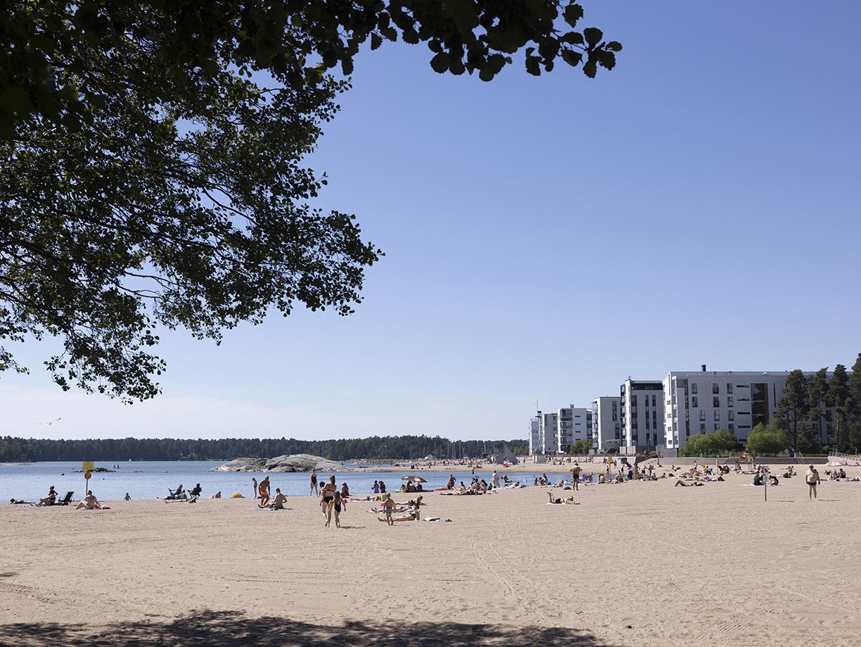 Laaja hiekkaranta ja auringonottajia.