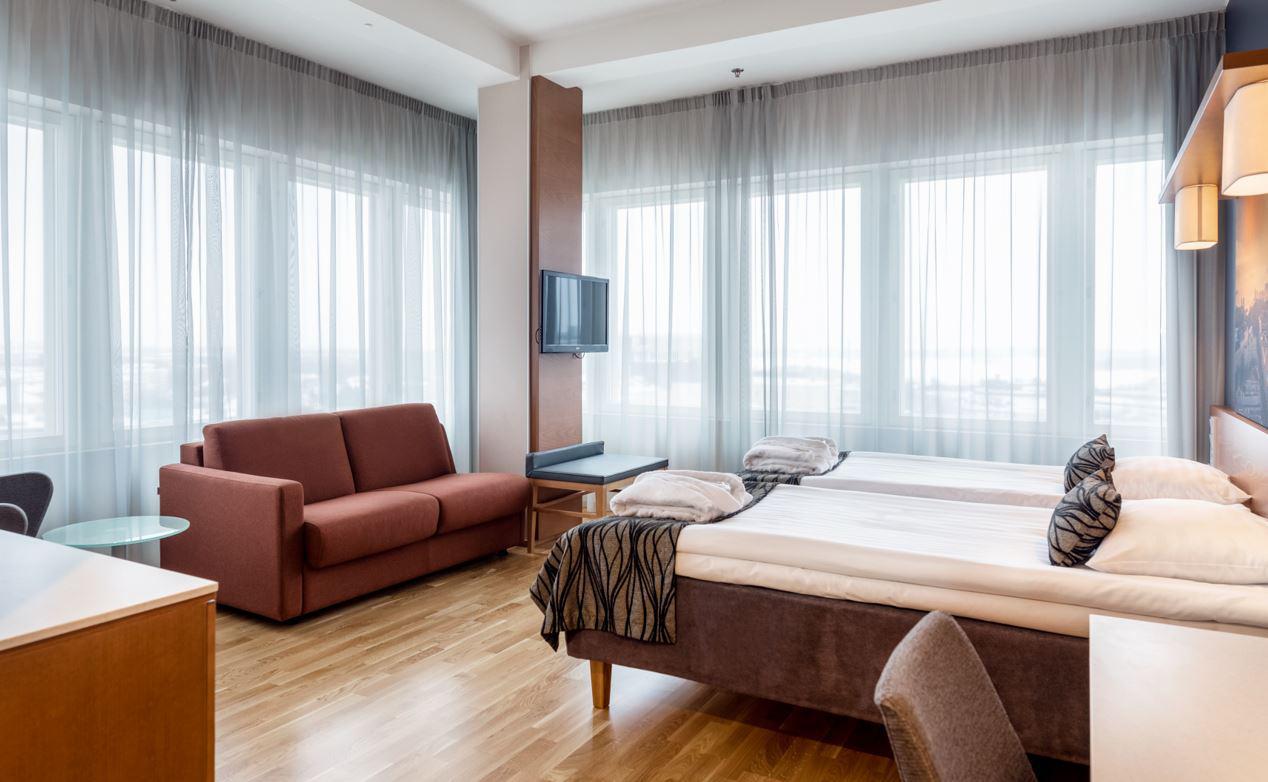 Scandic Meilahden hotellihuone, sänky ja punainen sohva.