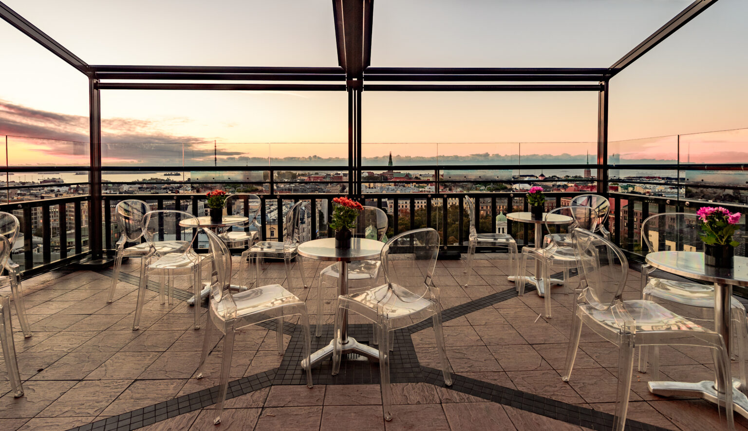 a rooftop patio with clear chairs and tables