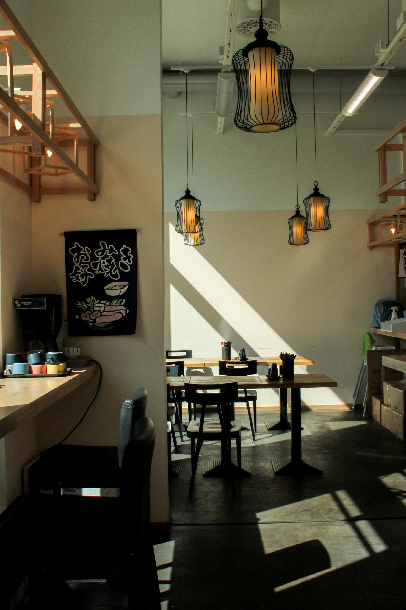 Restaurant Mashiro seen from the inside. A table lit by sunlight, with lamps hanging from the ceiling.