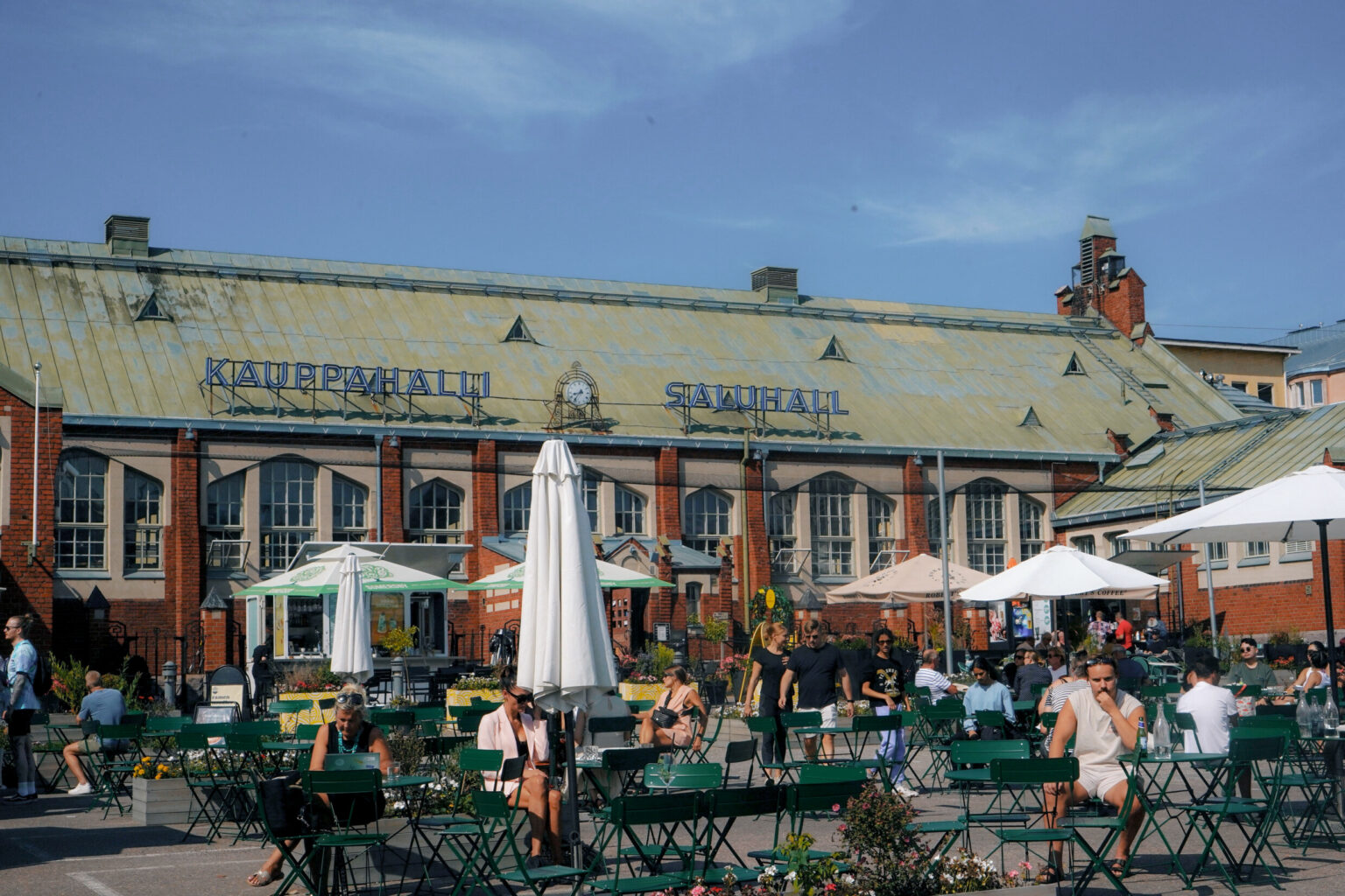 People sitting outside the Hietalahti Market Hall in Helsinki in the summer.
