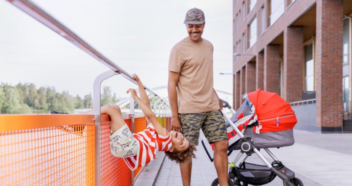 Father and son playing by a stroller on a sunny day.