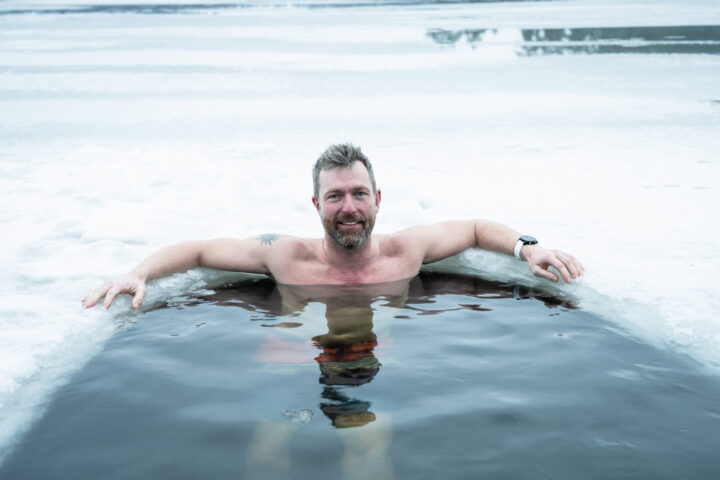 Man smiling in an ice bath surrounded by snow and ice