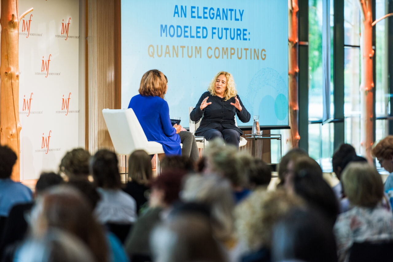 Two women discuss quantum computing on stage at an International Women's Forum event.
