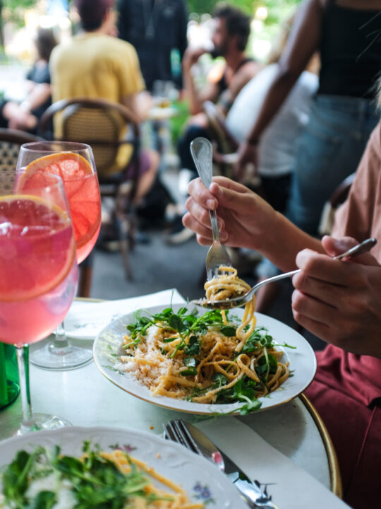 Couple enjoying pasta and cocktails at an outdoor cafe