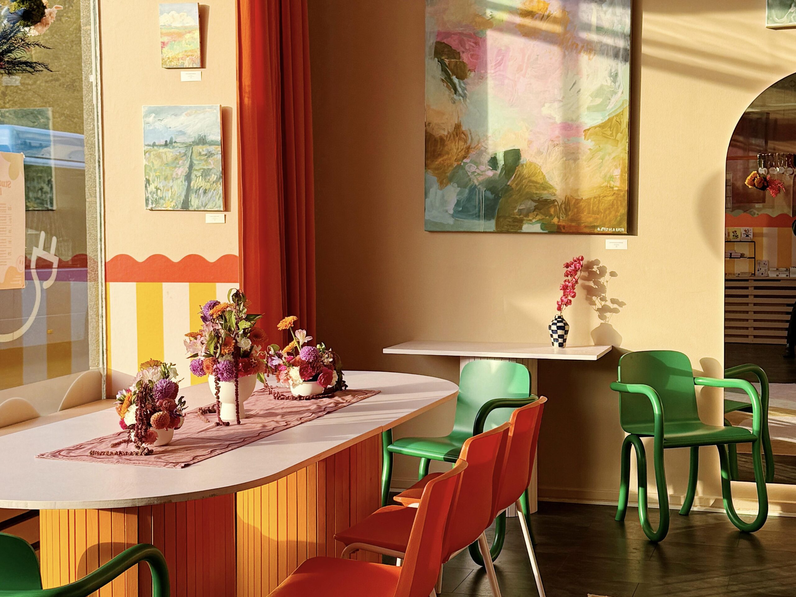 Designkaverit Studio's interior. Tables with chairs, and in the background on the wall there are paintings.