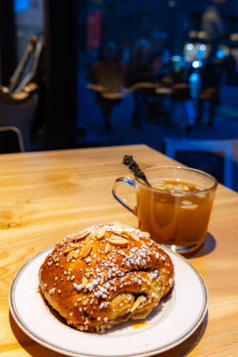 Swedish cinnamon bun (kanelbulle) with almonds and pearl sugar next to a cup of tea