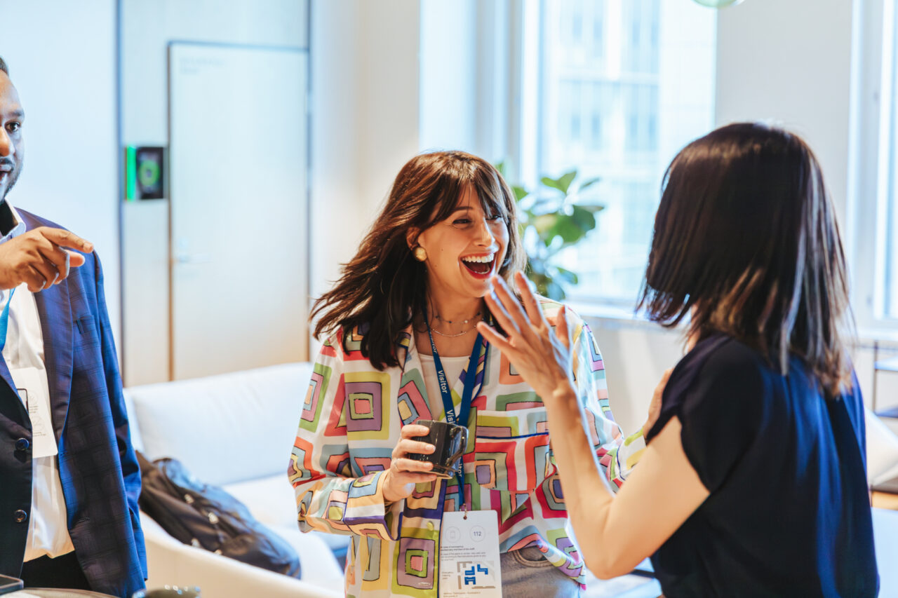 a woman laughing while another woman is holding a cup