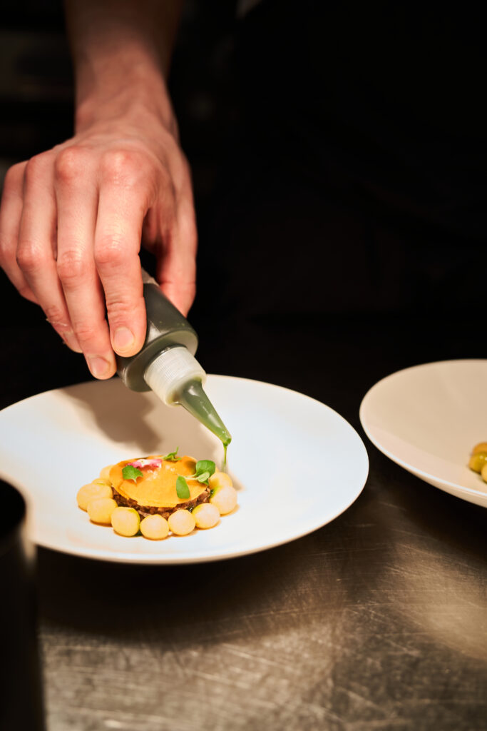 Chef garnishing a gourmet dish at Finnjavel Salon