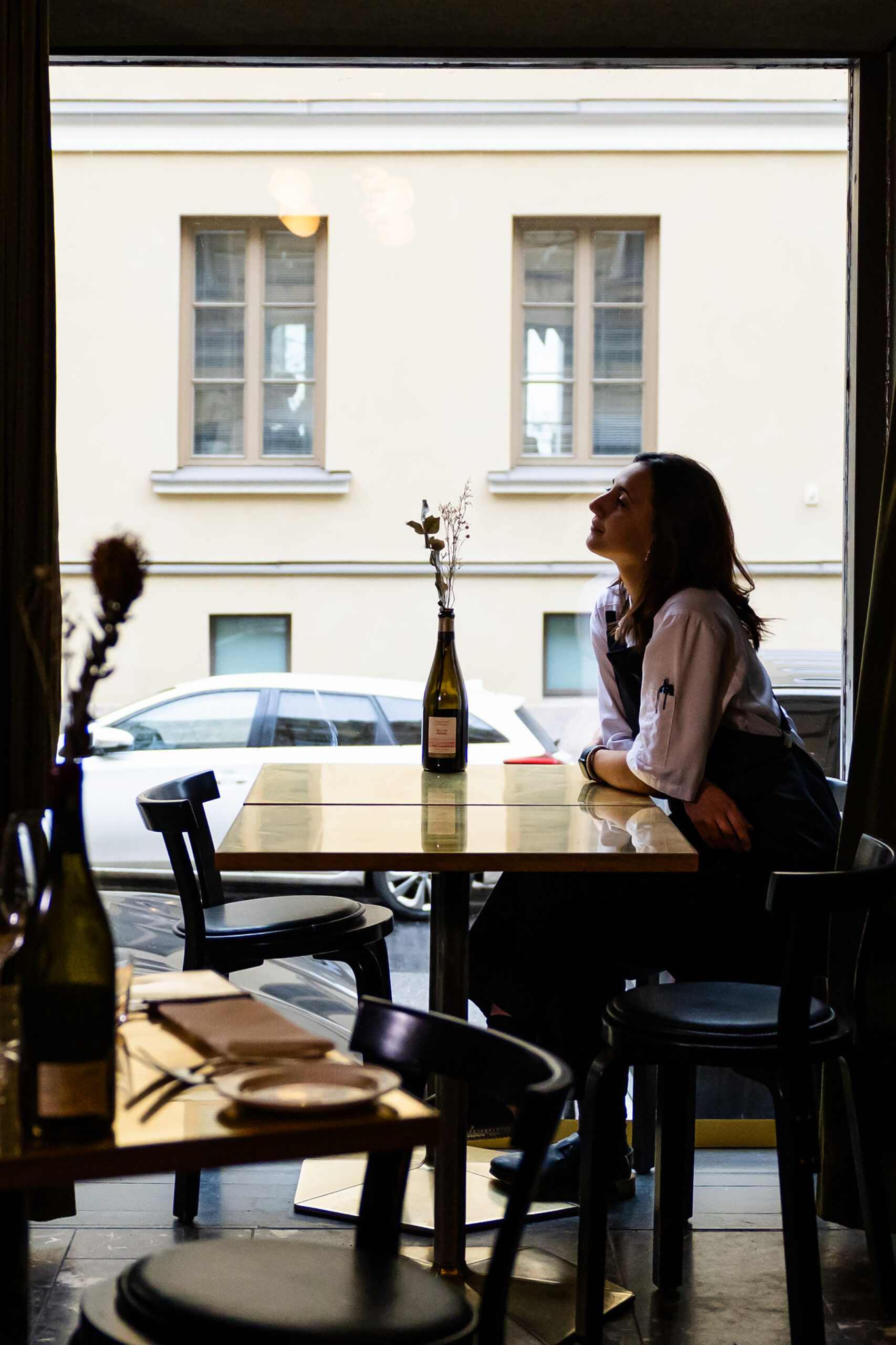 a woman sitting at a table looking out a window
