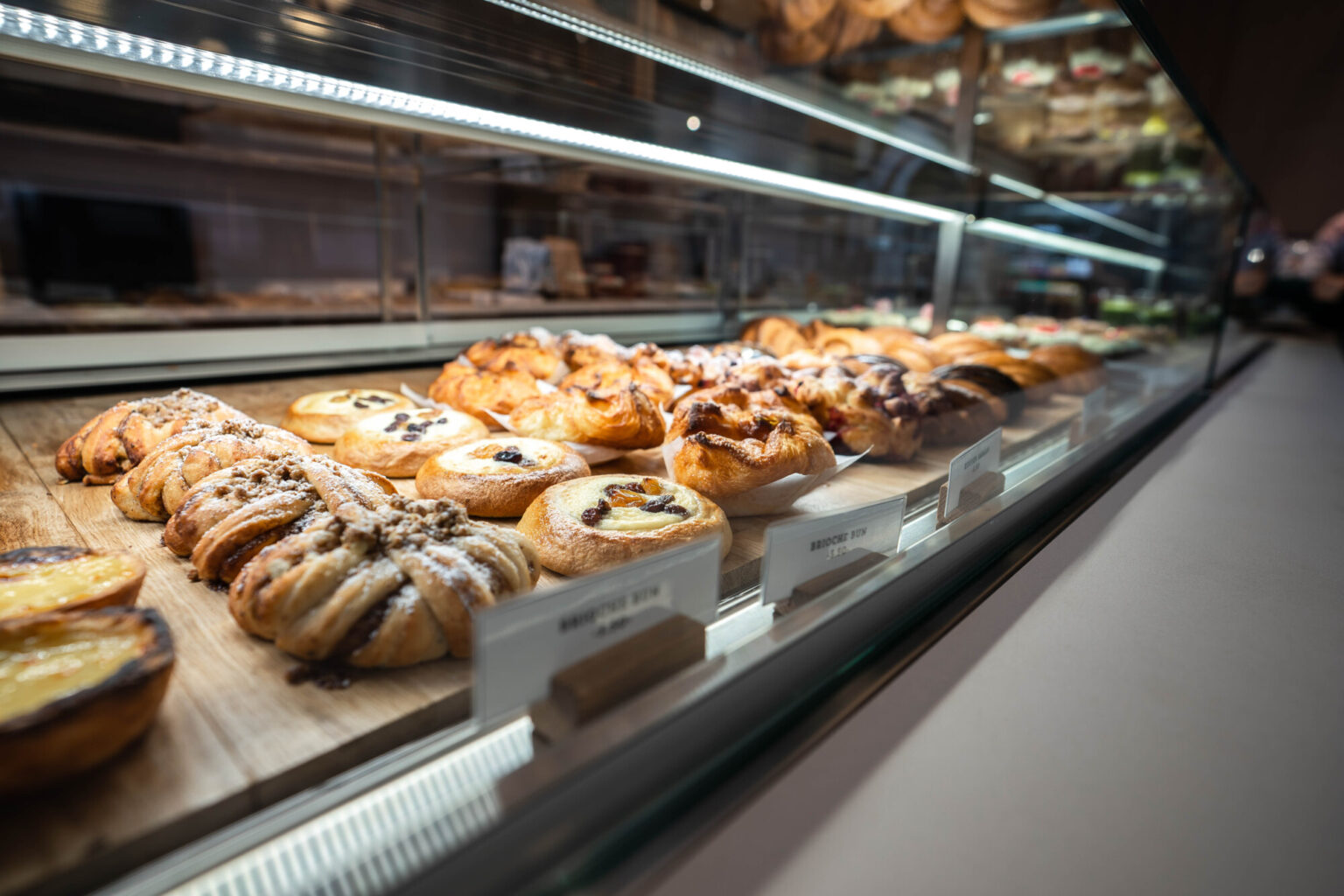 Assortment of freshly baked pastries, including danishes and buns, displayed in a bakery case.