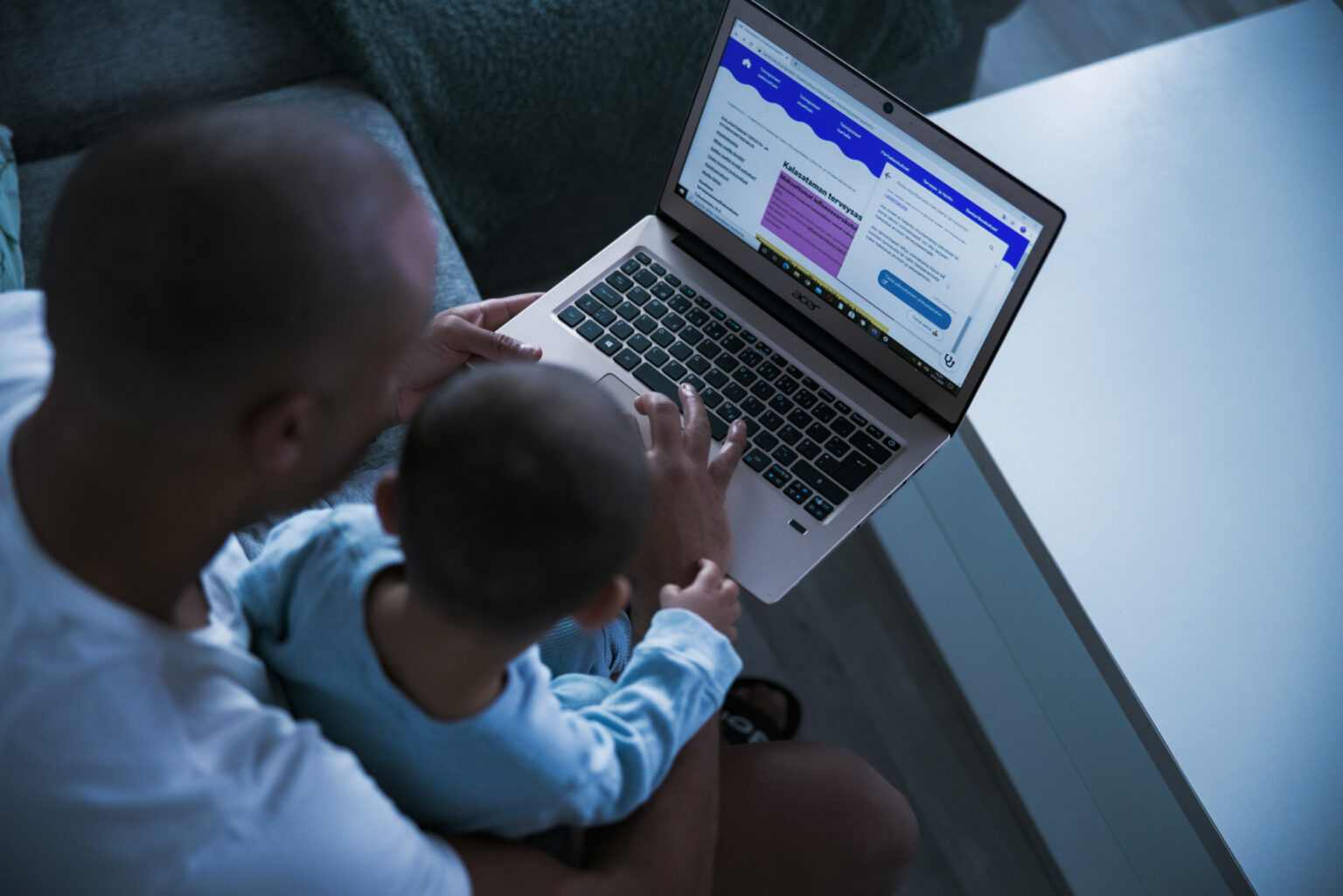 Dad and a baby using a computer at home.