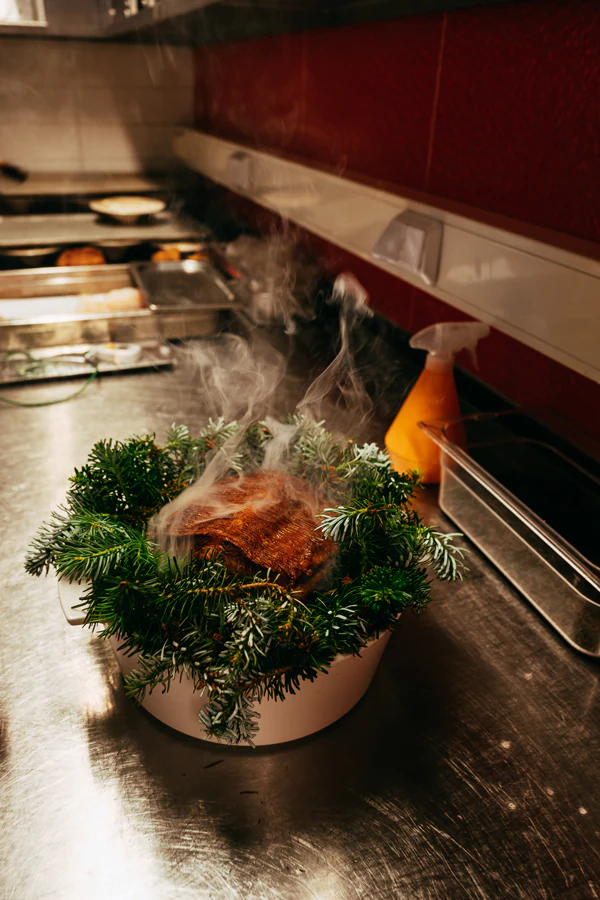 Smoky dish surrounded by greenery from Restaurant Olo.