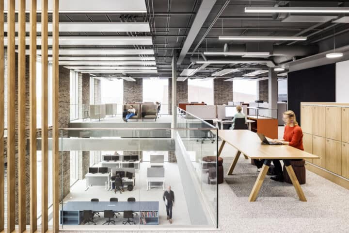 Modern office interior with open workspaces, desks, and natural light.