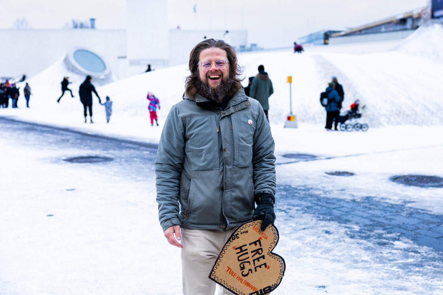A man holding a heart shaped sign in snowy Helsinki.