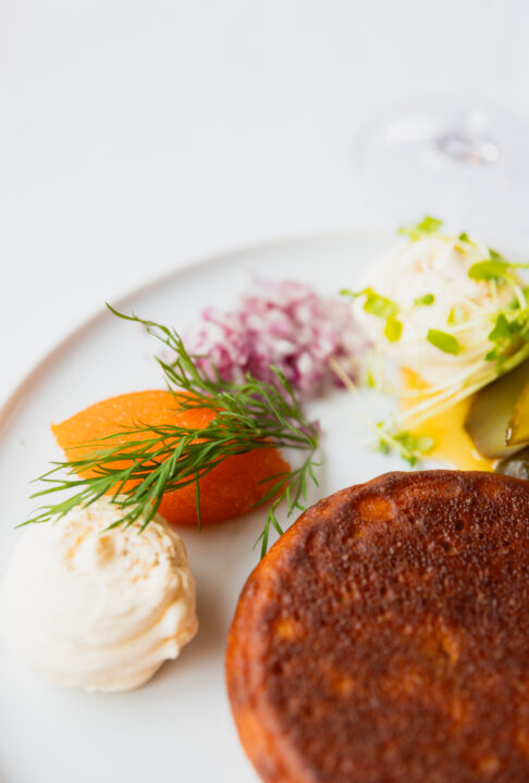 Gourmet smoked salmon potato pancake with caviar, dill, creme fraiche, and pickled onions