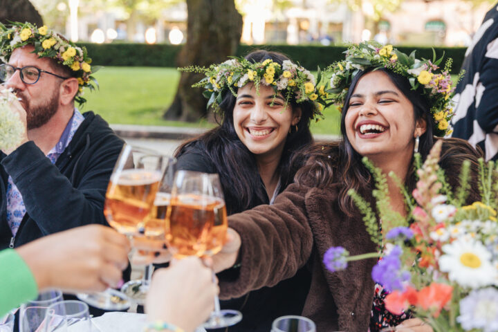 Friends in flower crowns toast with champagne at an outdoor celebration