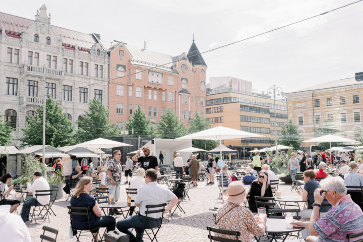 People enjoying outdoor dining at a European city square with historic buildings