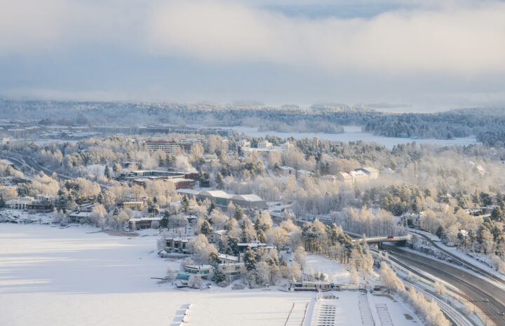 Snow-covered Finnish landscape with frozen lake, trees, and highway.