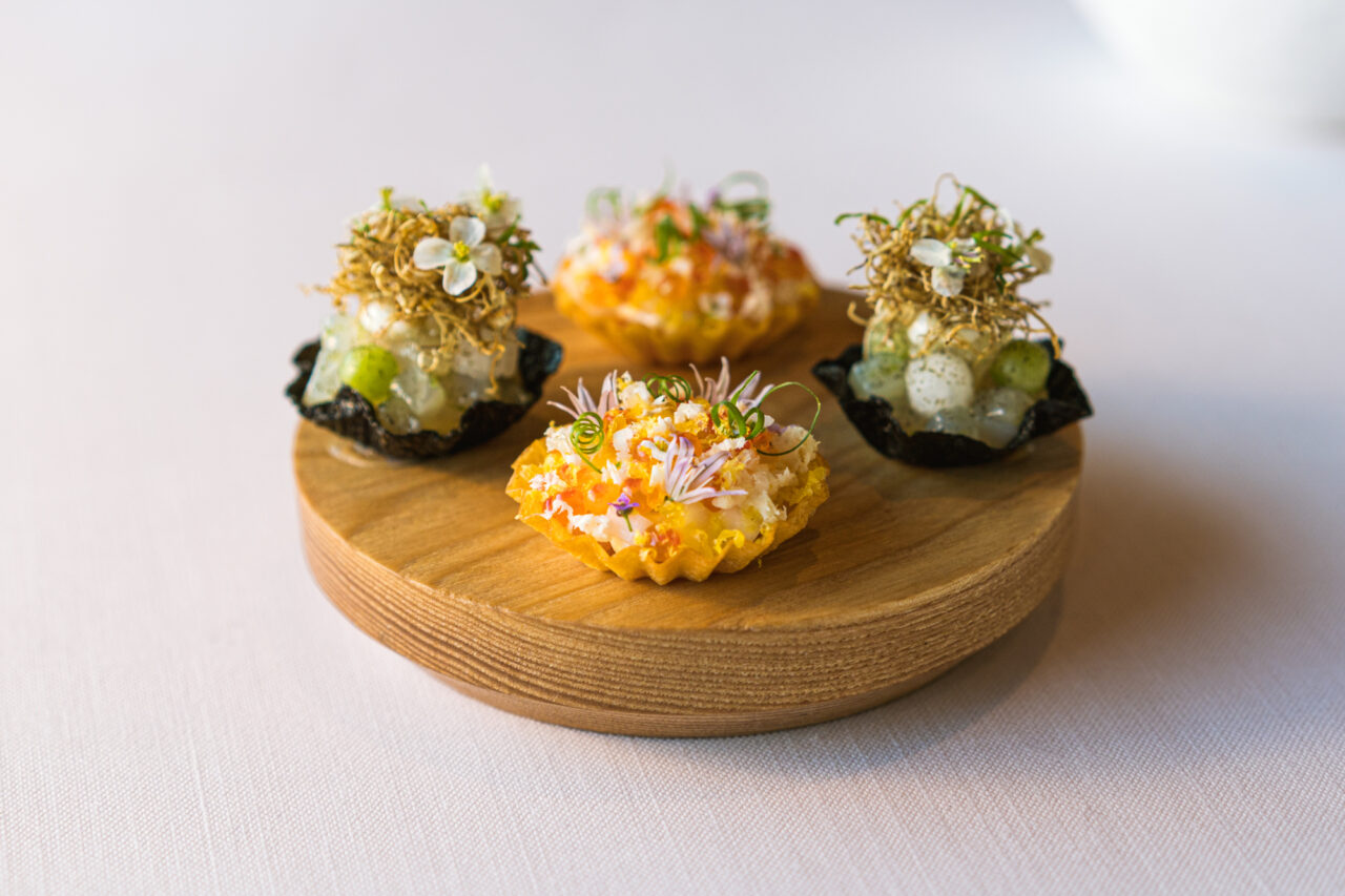 Gourmet appetizers: delicate bites with edible flowers and herbs on a wooden platter