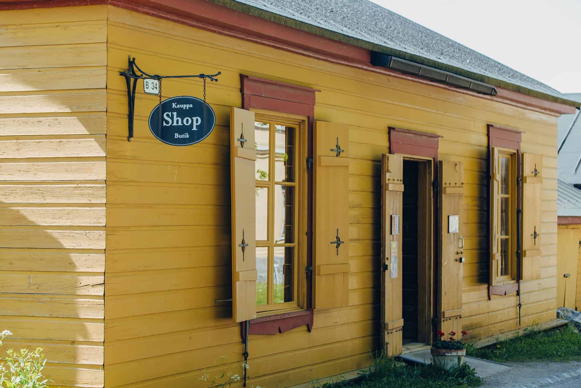 Kesäkauppa Suomenlinnassa. Keltainen rakennus, jossa on kyltti tekstillä Shop.