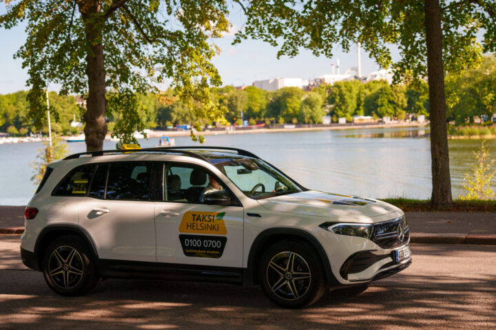 A Helsinki taxi driving by a waterfront.