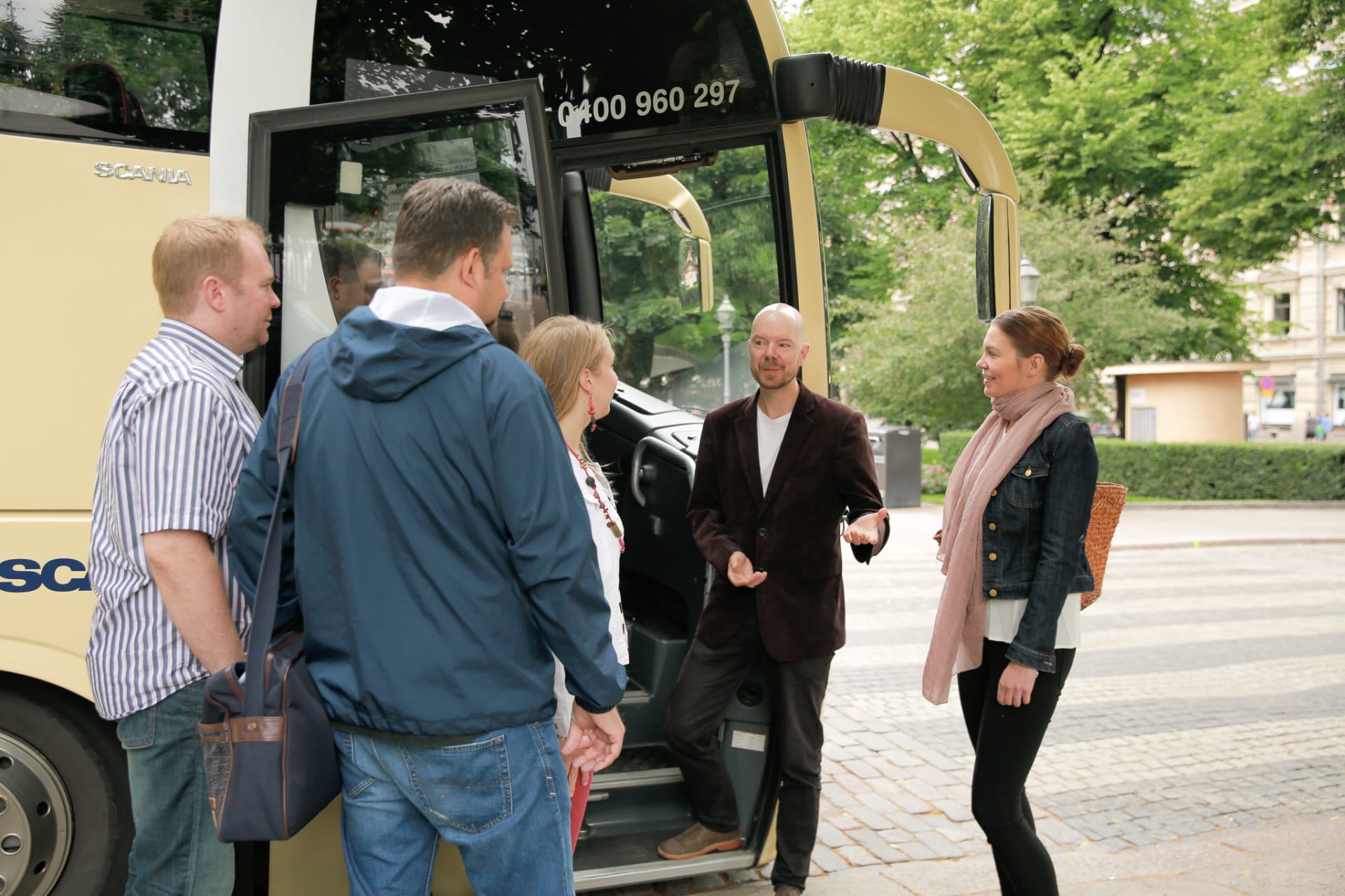 Guide welcoming a group of customers to a tour bus
