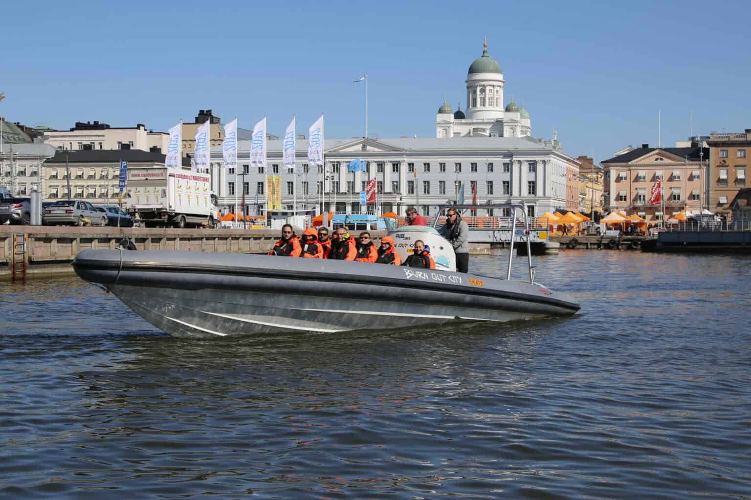 RIB boat tour with passengers in Helsinki, Finland, with Helsinki Cathedral in background.