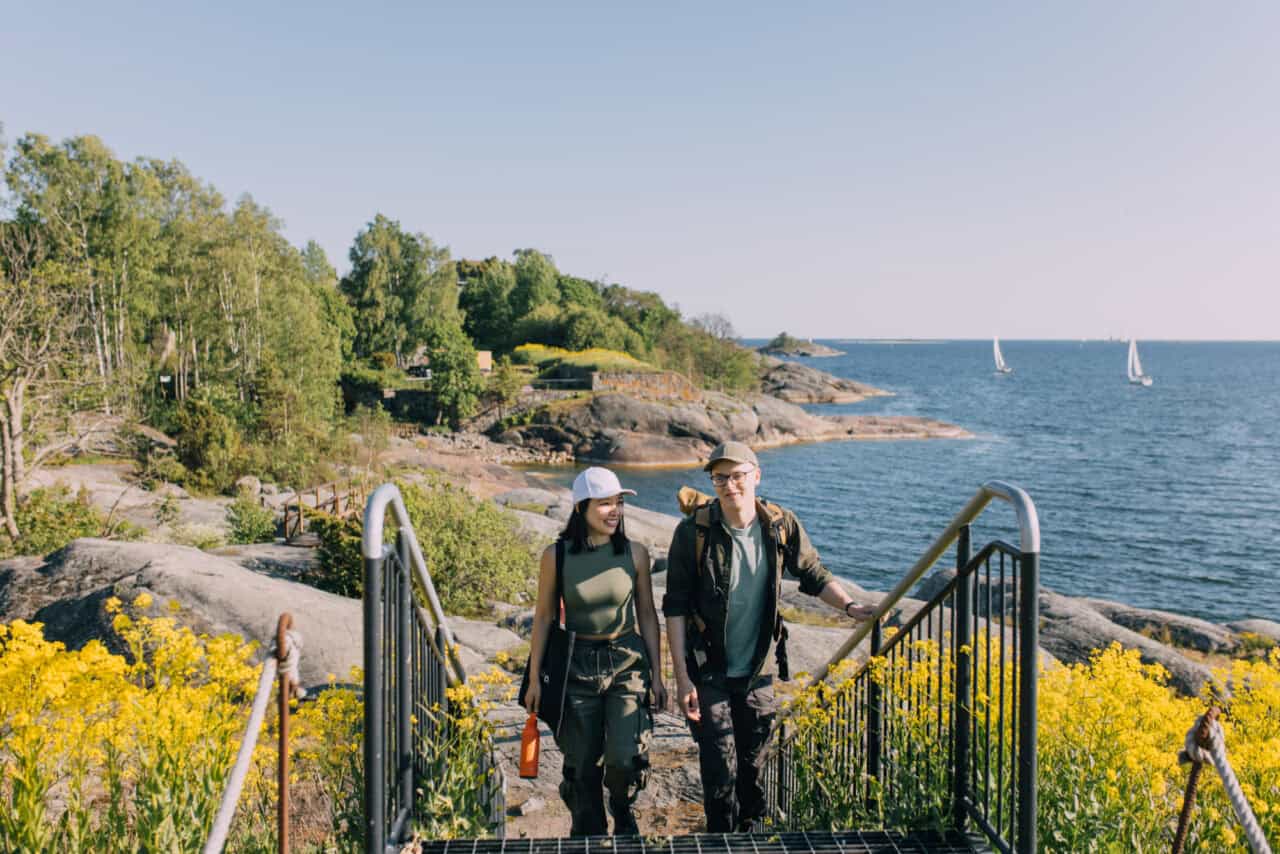 Couple hiking down stairs by the sea with yellow flowers