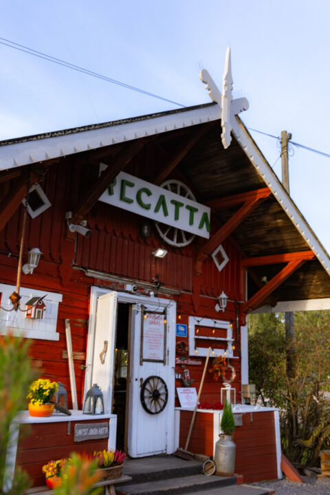 Red building with "Tecatta" sign, flowers, lanterns, and a wheel