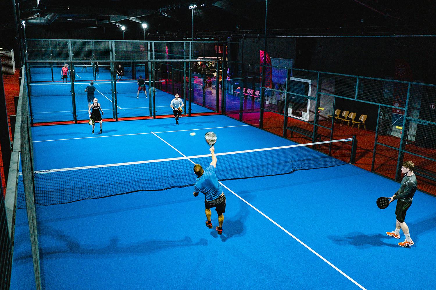 Padelspelare på Social Sports Clubs padel planer. I bakgrunden syns lounge området.