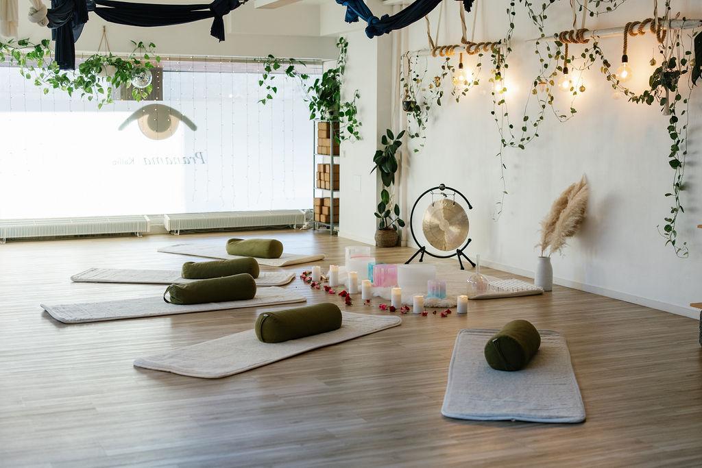 Pranama Kallio, the yoga studio photographed from the inside. There are yoga mats and candles on the floor. Indoor plants on the ceiling.
