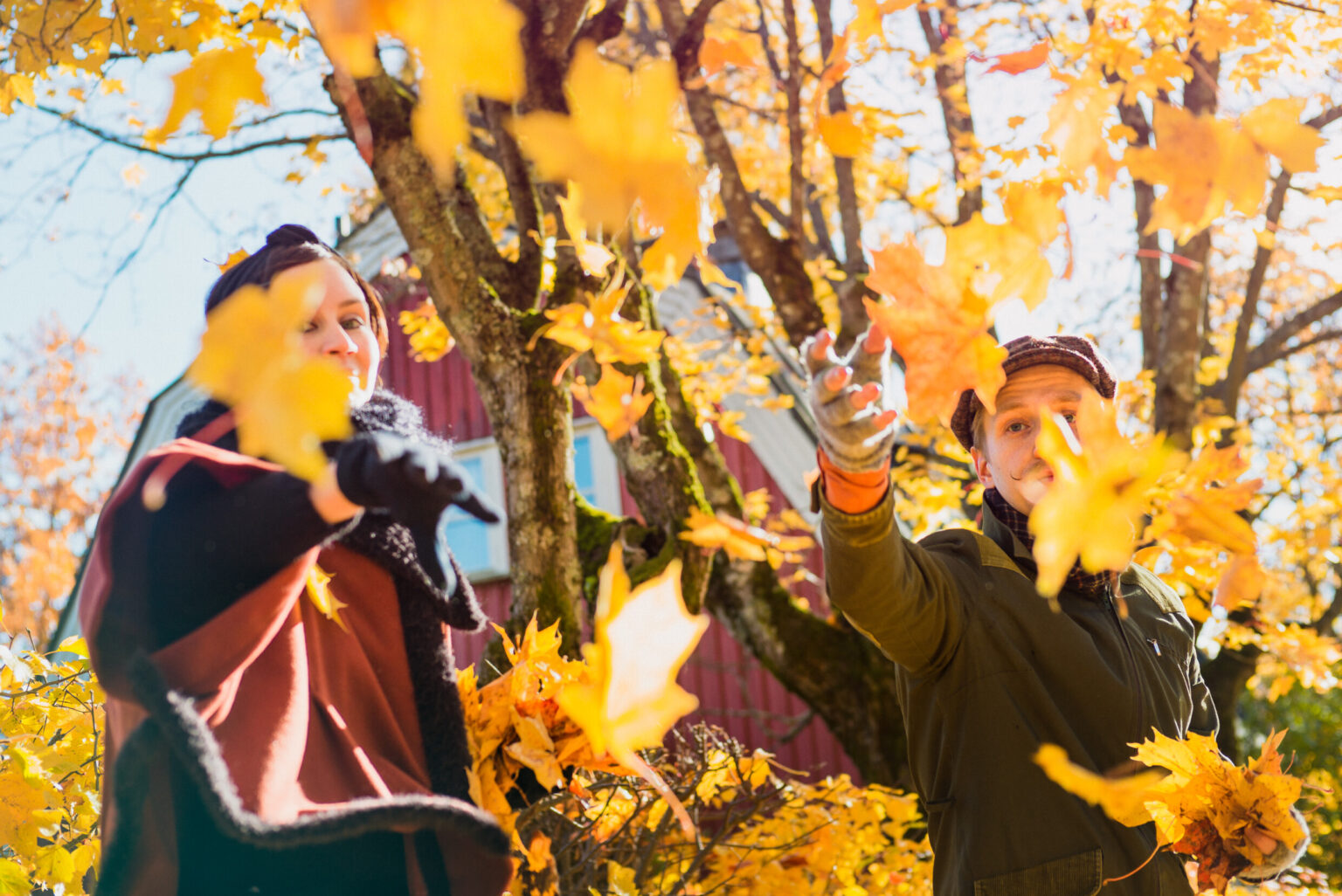 Couple throwing autumn leaves onto the camera in Helsinki.