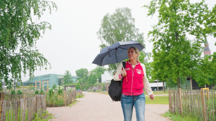 Mette Ingstrup, a business event organiser, walking under an umbrella in the Töölönlahti Park, Helsinki.