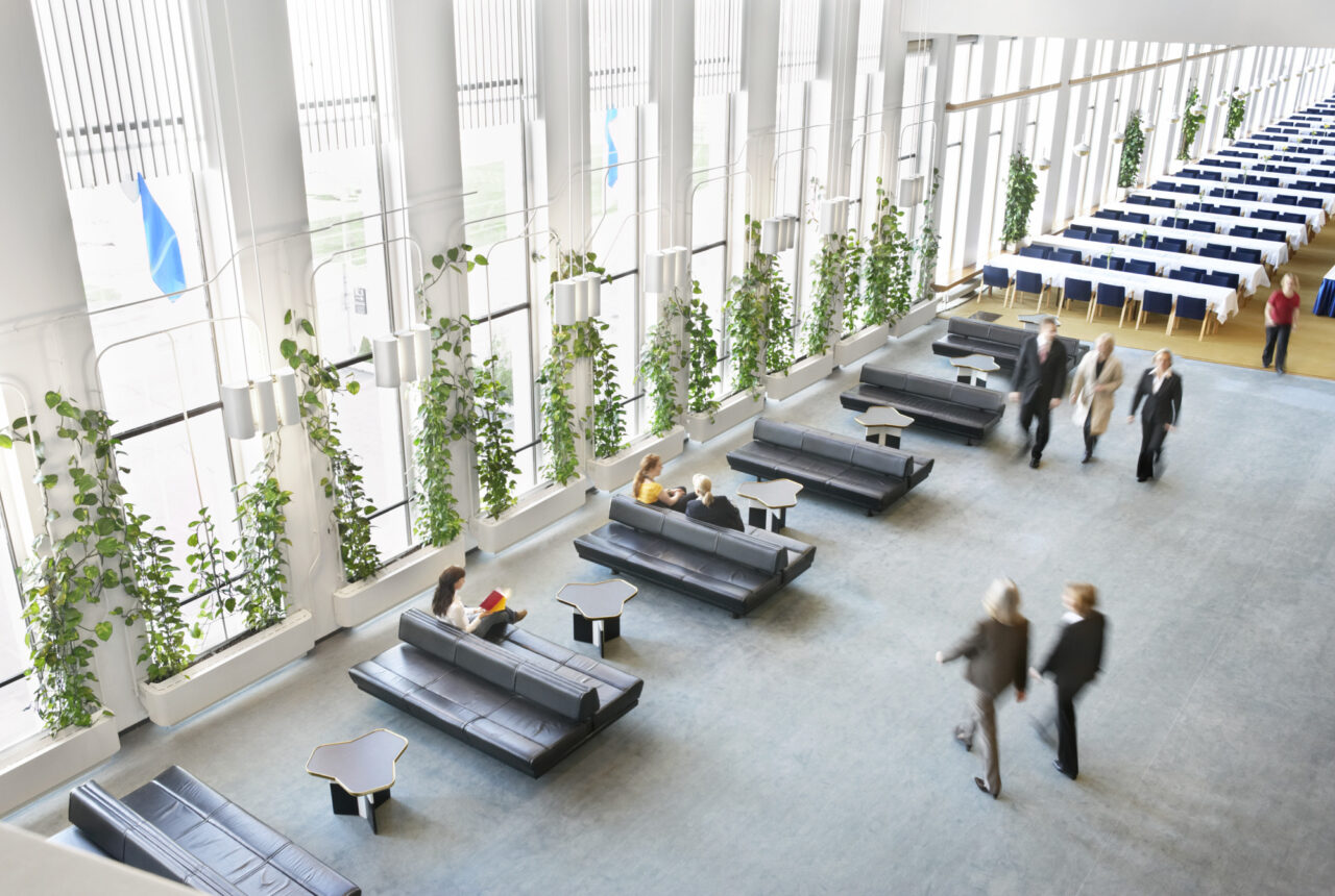 Modern conference venue lobby with people, plants, and seating areas