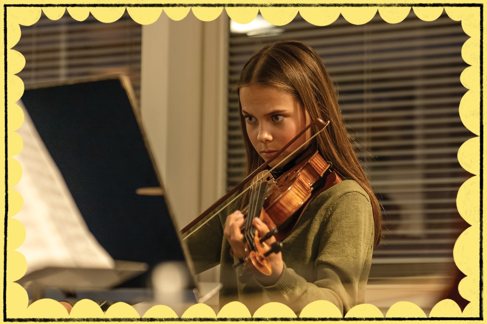 Tyttö soittaa keskittyneesti viulua ja katsoo nuotteja nuottitelineessä olevasta nuottivihkosta.