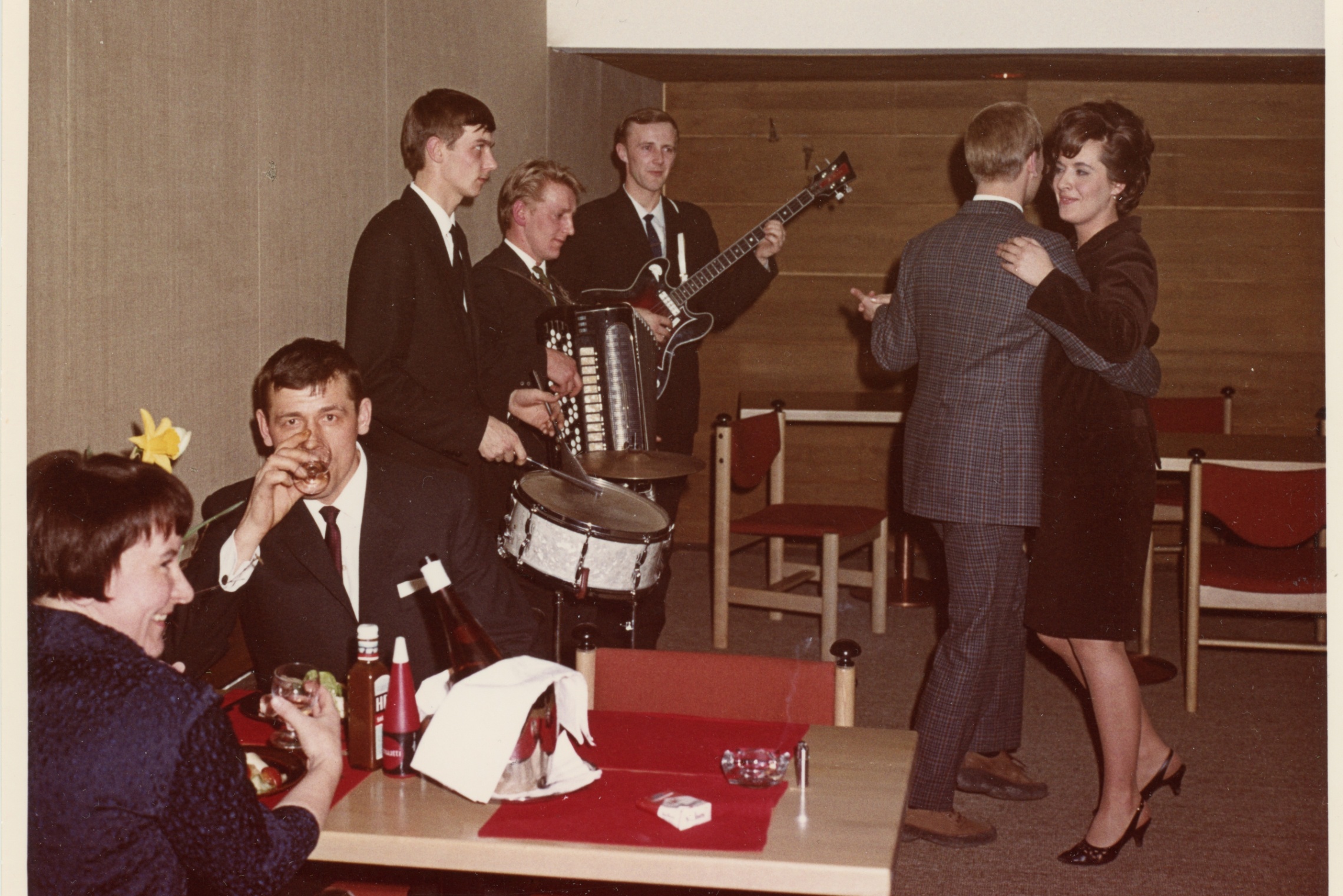 Ravintolan asiakkaita istumassa pöydän ääressä ja tanssimassa orkesterin edustalla