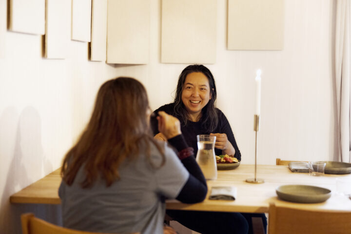 Two women enjoying a meal at a table in a warmly lit dining room.