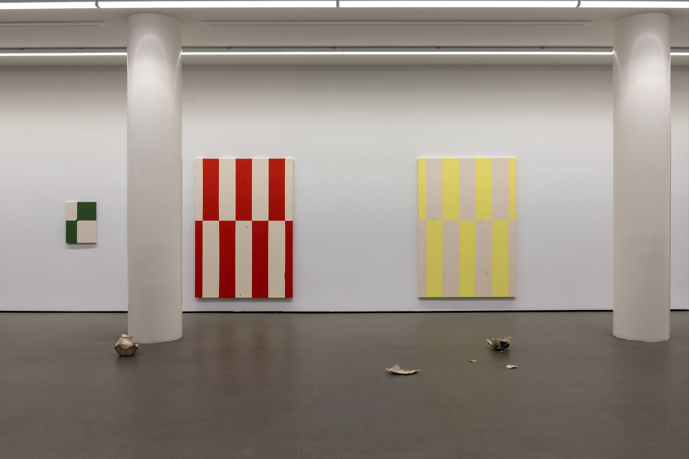 Valkoinen näyttelytila jossa maalauksia seinällä