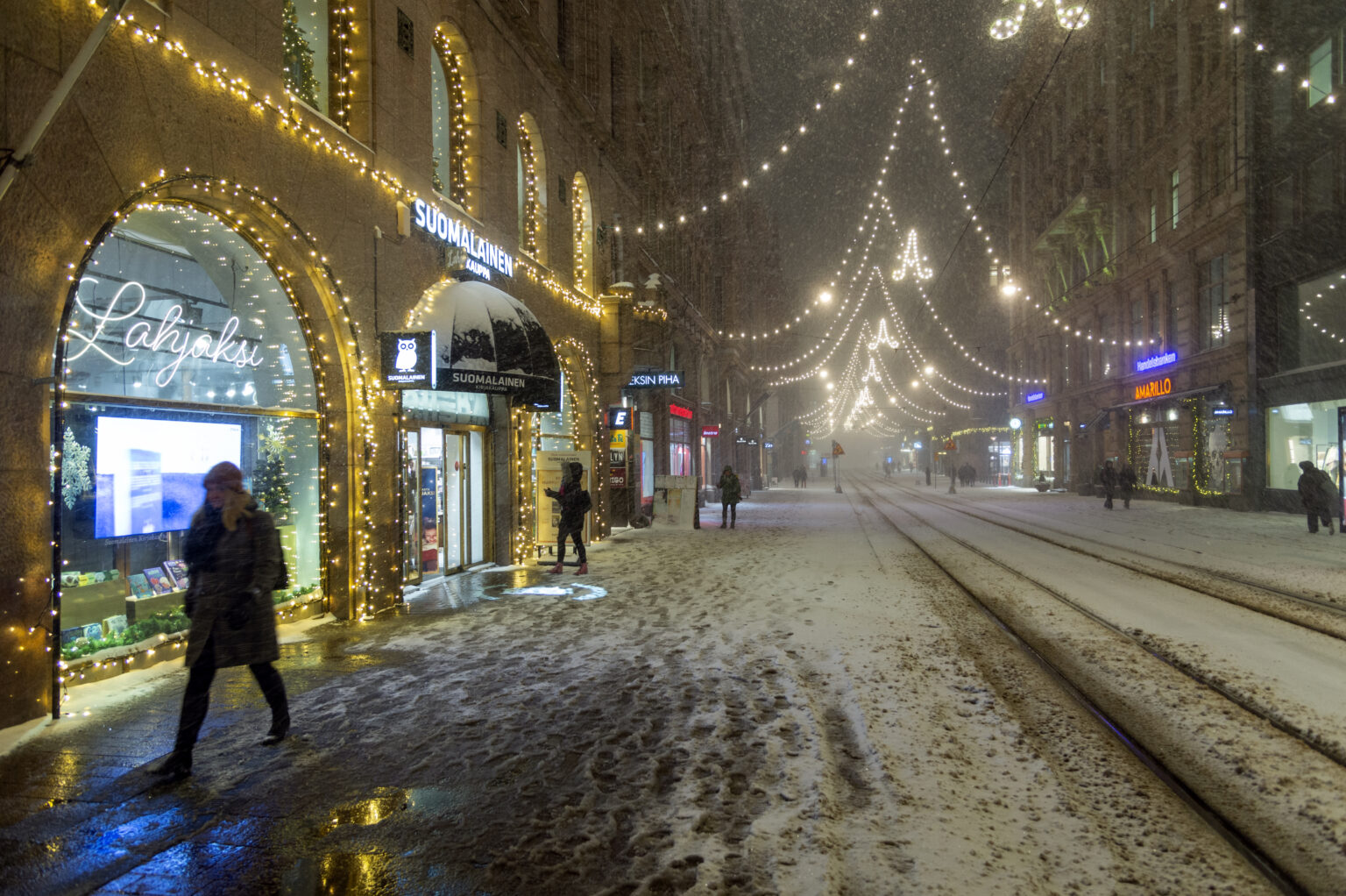 Snowy Helsinki street with tram tracks and festive lights