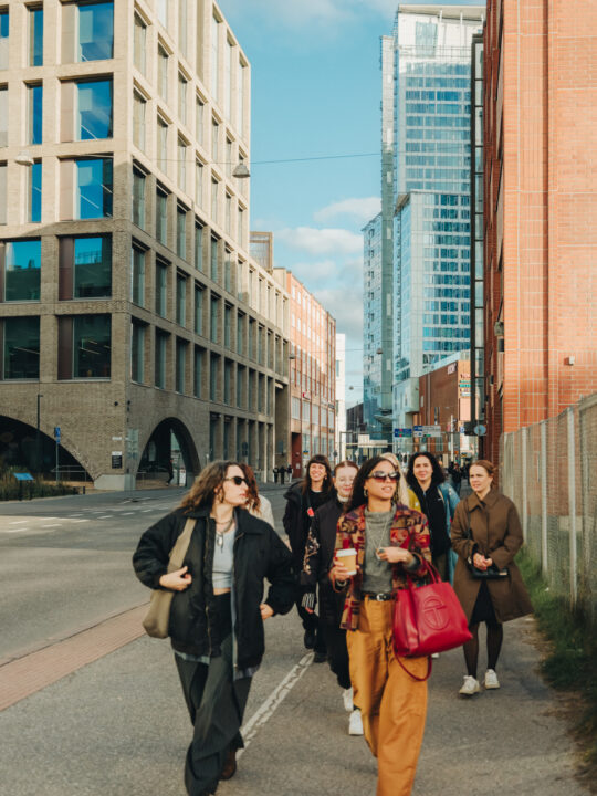 Group of young women walking down a city street with modern architecture