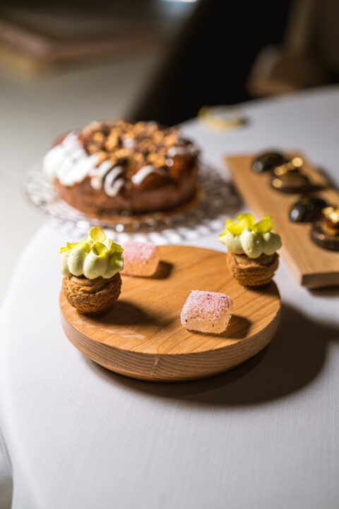 Gourmet desserts: mini cream puffs with pistachios, pink jellies, and a caramel nut cake.
