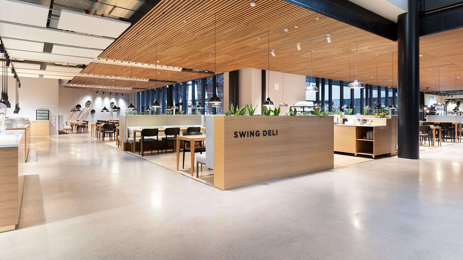 Swing Deli, kuvattuna ravintolan ulkopuolelta. Kuvassa näkyy ravintolasali, jossa on pöytiä ja tuoleja.