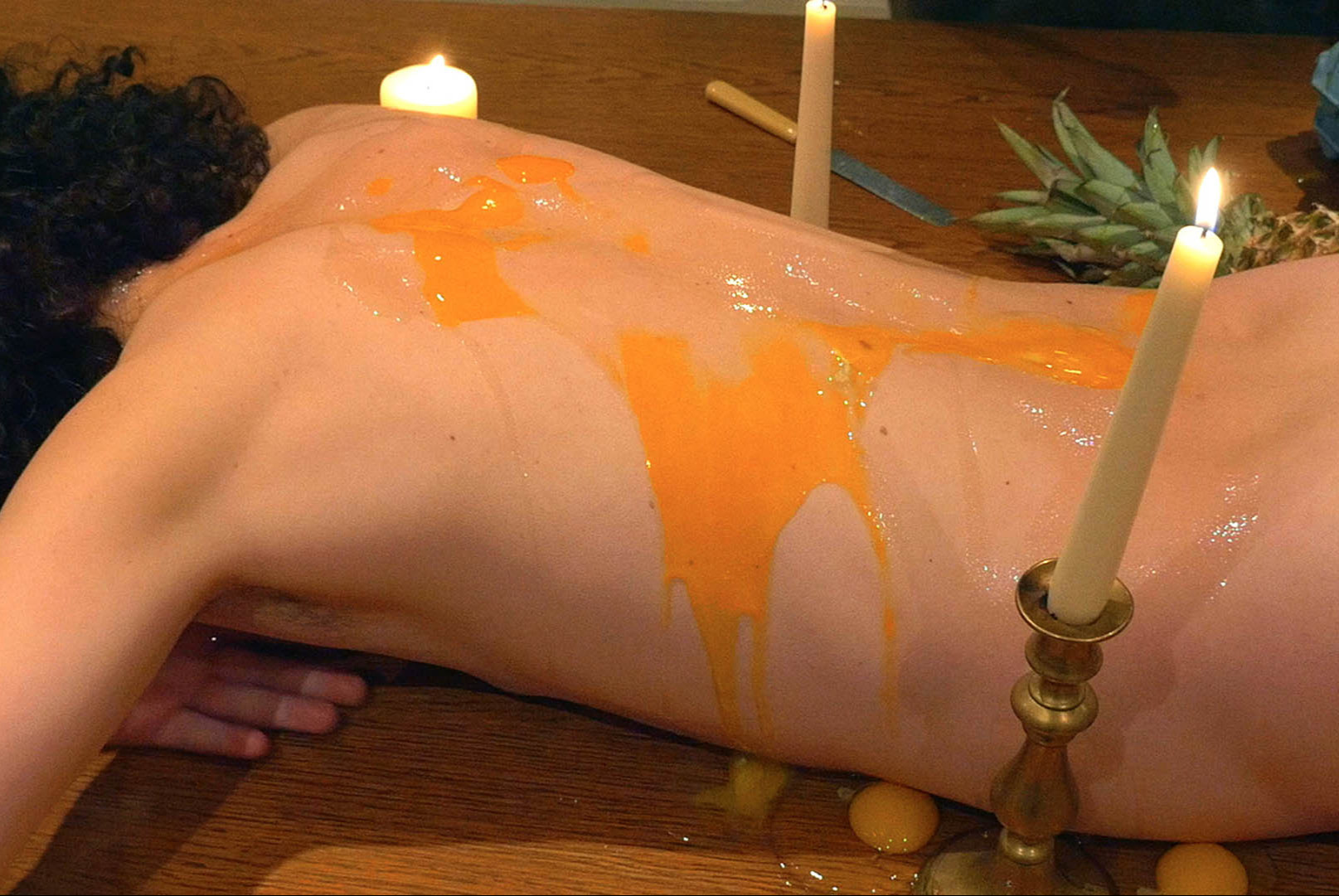 Henkilö makaa vatsallaan, selän päällä rikottuja kananmunia.