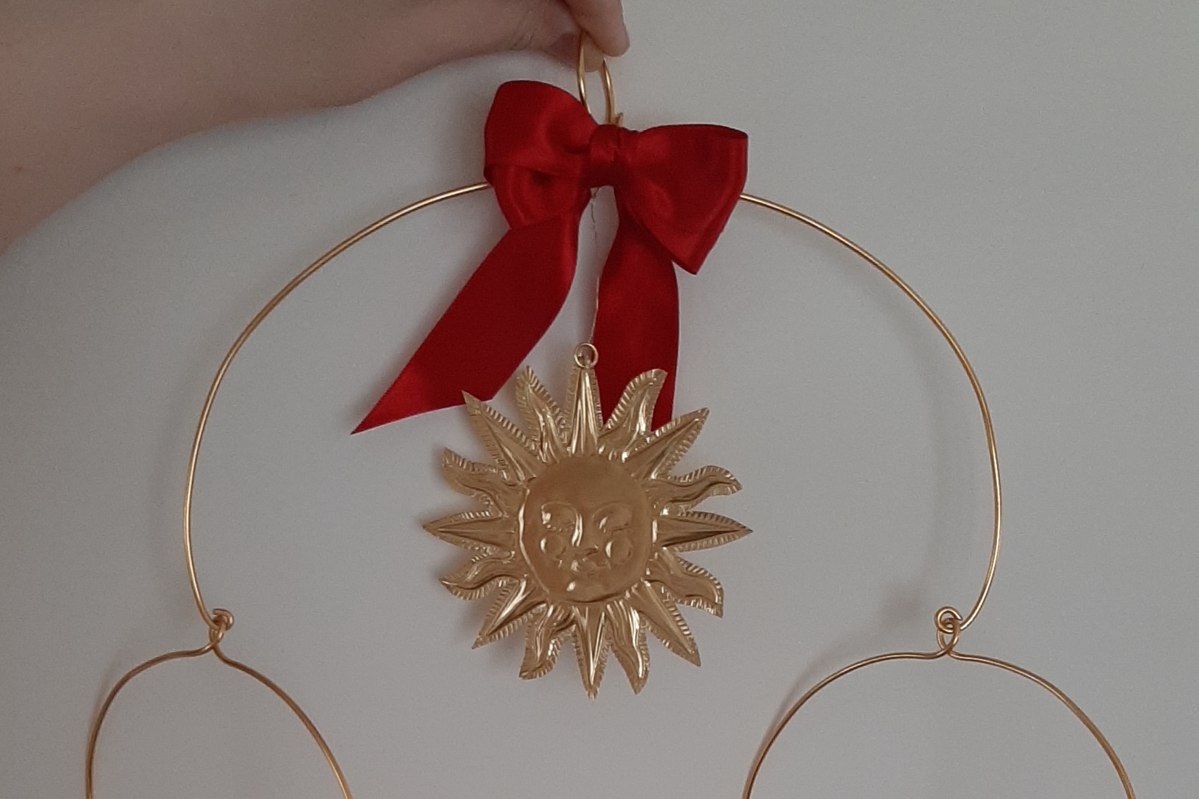 Kuvassa on kultainen mobile, jossa on aurinko, kuu ja tähdet.