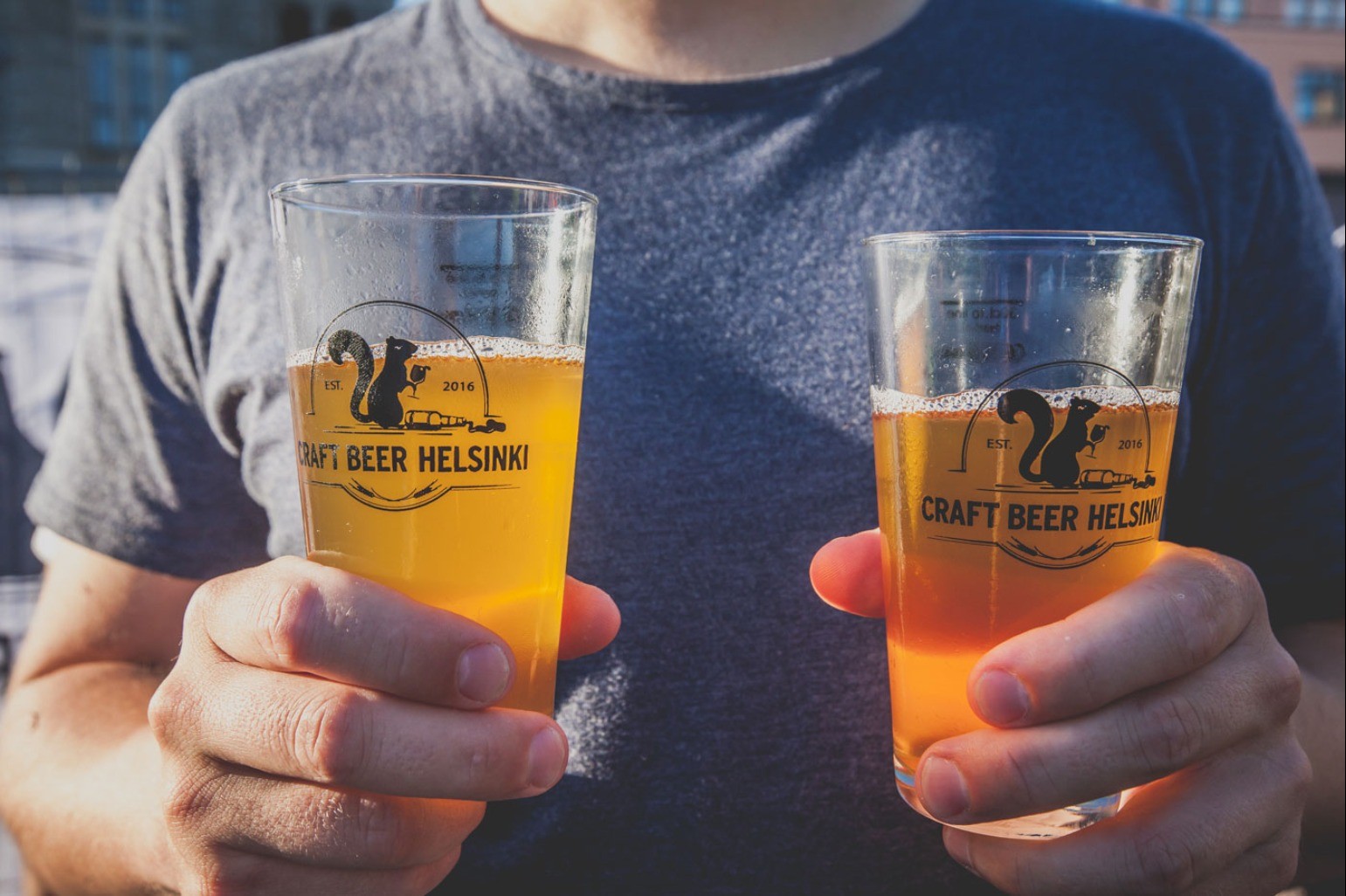 Ihminen käsissään kaksi olutlasia